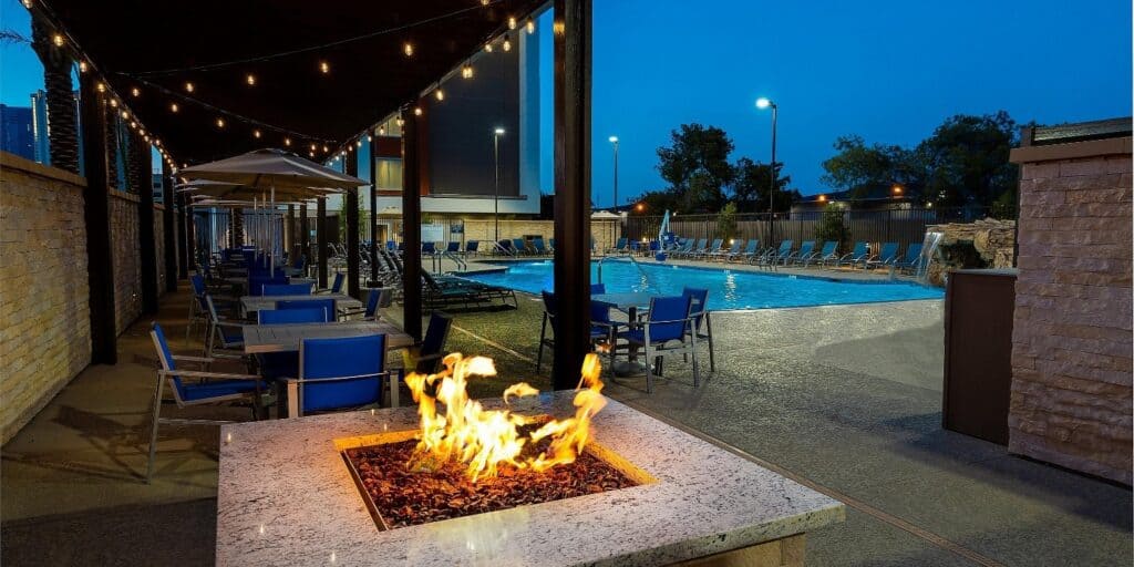 Hotel pool in the background with a lit fire pit just in front of the pool deck area.