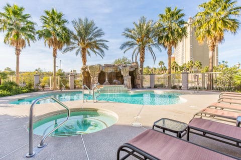 Hotel pool in the background with a small hot tub in the foreground. Loungers can be see along the right side of the photo.