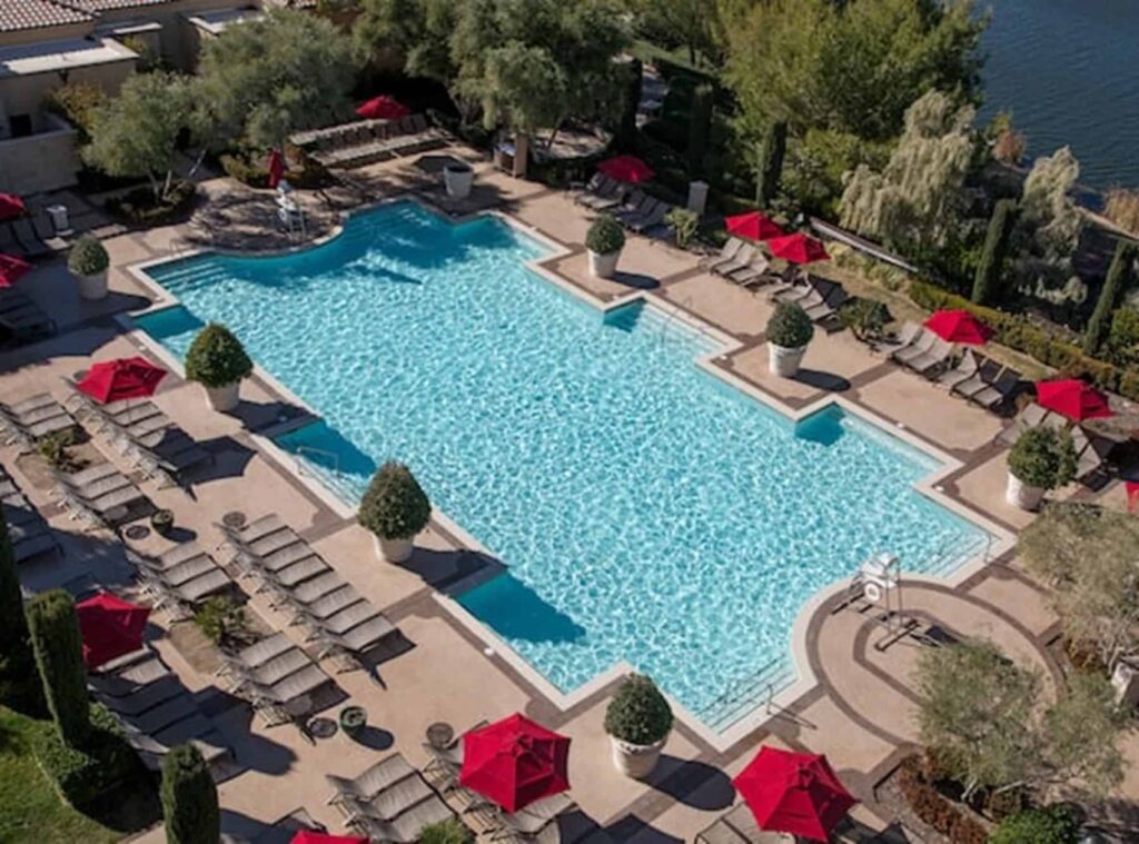 Overhead photo of hotel pool showing loungers and tables with sun umbrellas.