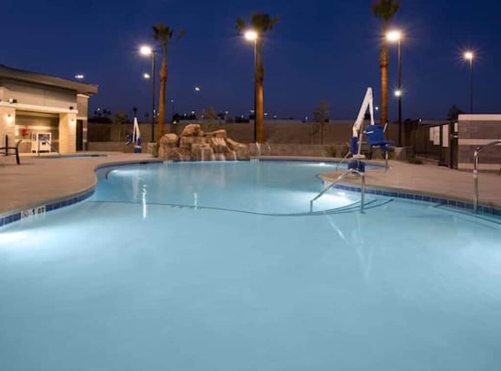 Hotel pool at night with overlights shining on the pool and pool deck
