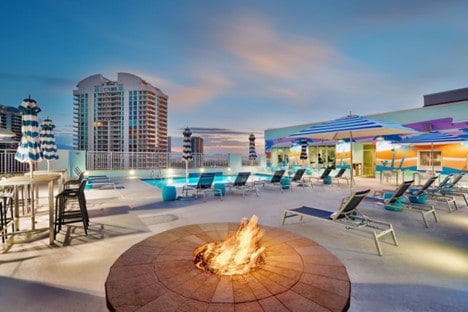 Hotel pool in background with lit firepit in foreground.