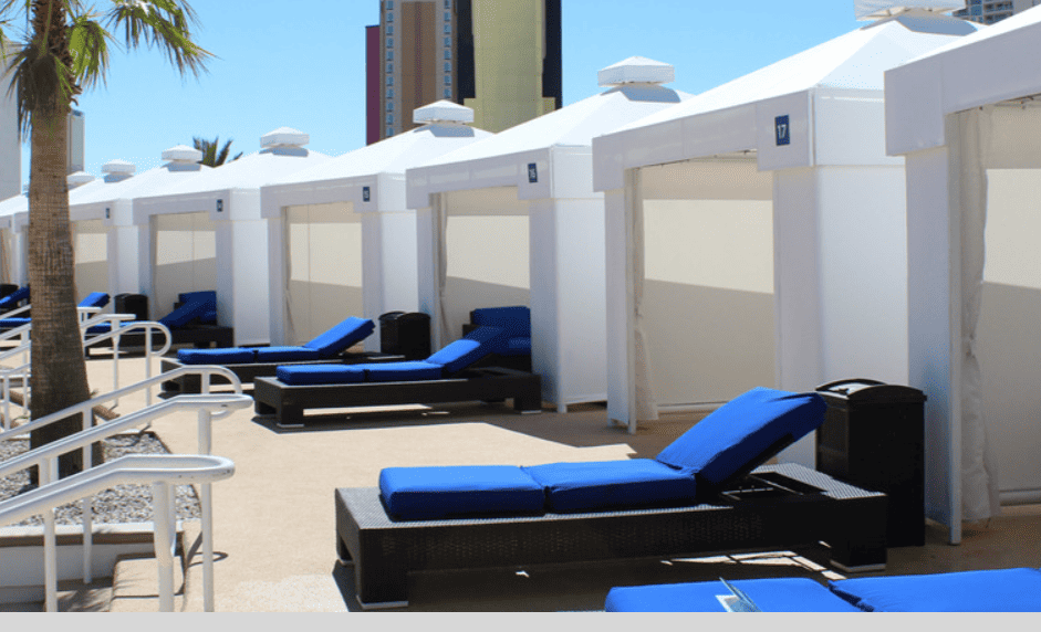 Pool cabanas with comfortable loungers in front.
