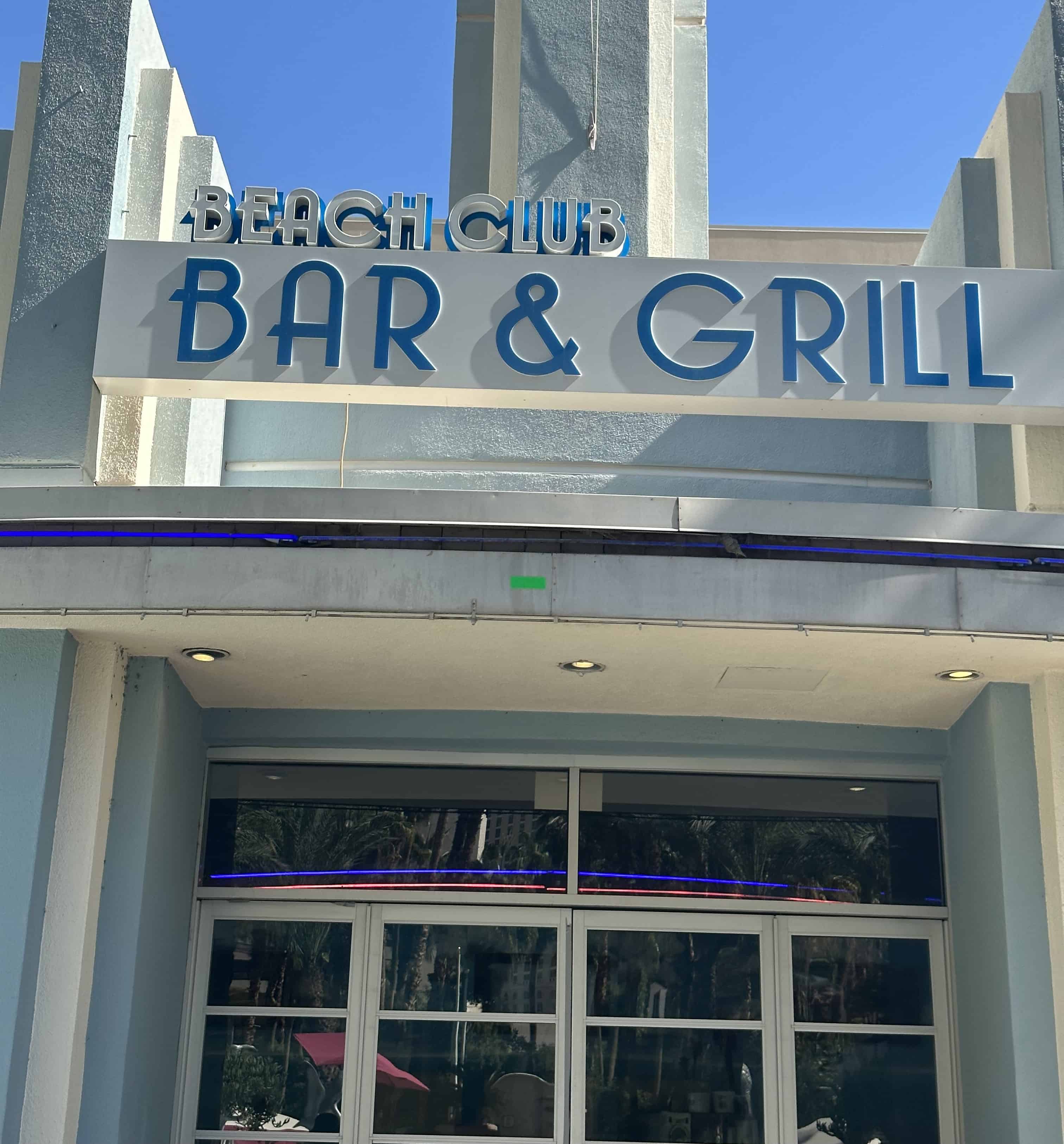 Outside view of the Beach Club Bar and Grill.  Large blue signage is above the entrance.