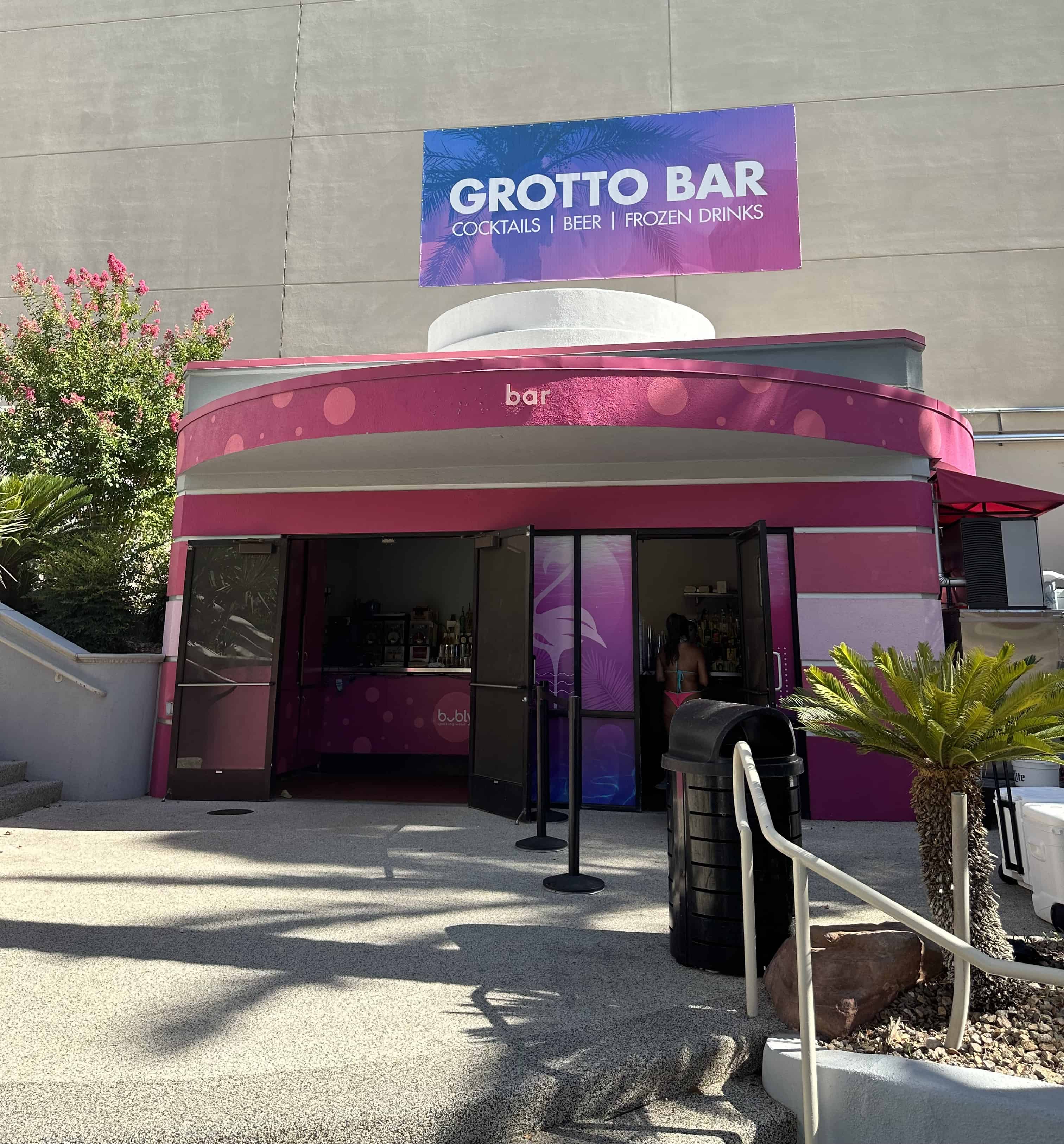 Outside view of the Grotto Bar. It has a large purple and red sign above a large red awning.