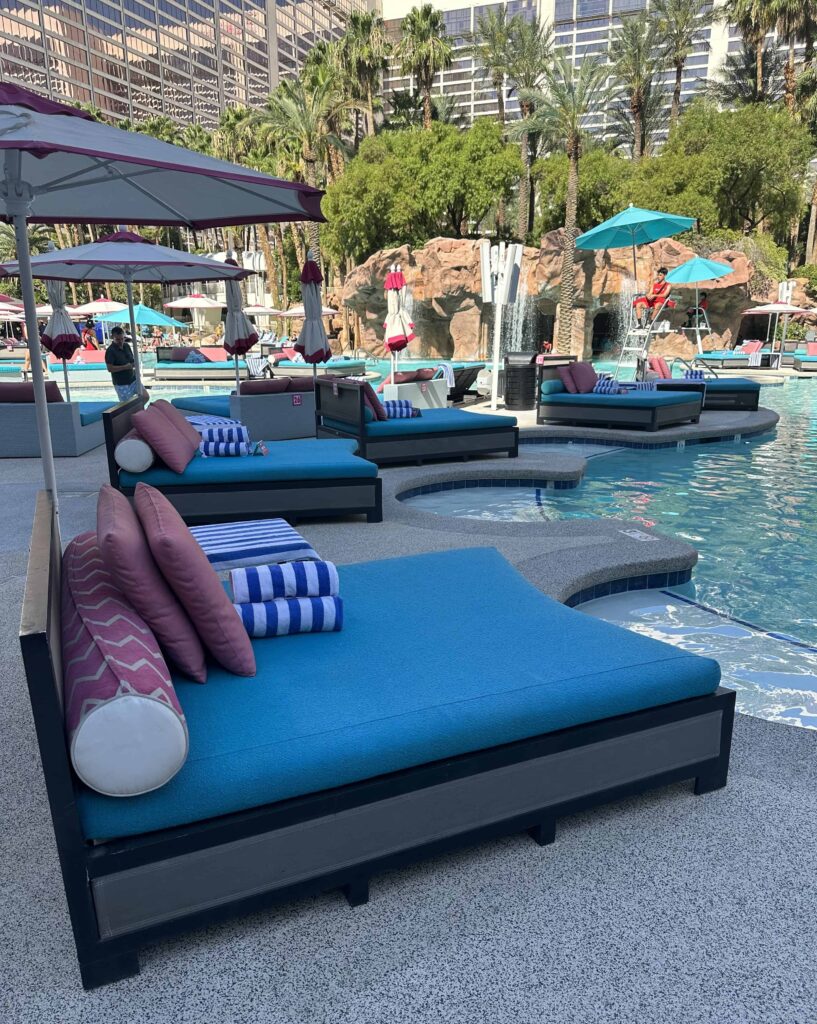 Daybeds with blue mattresses set up along side of pool.
