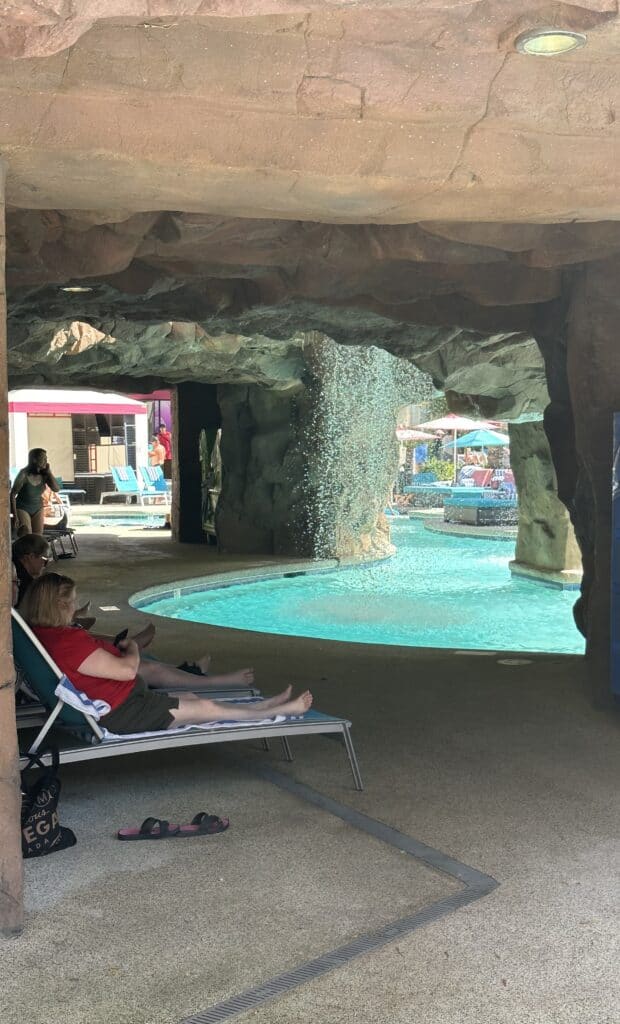 Guests relaxing in loungers in behind the waterfall.