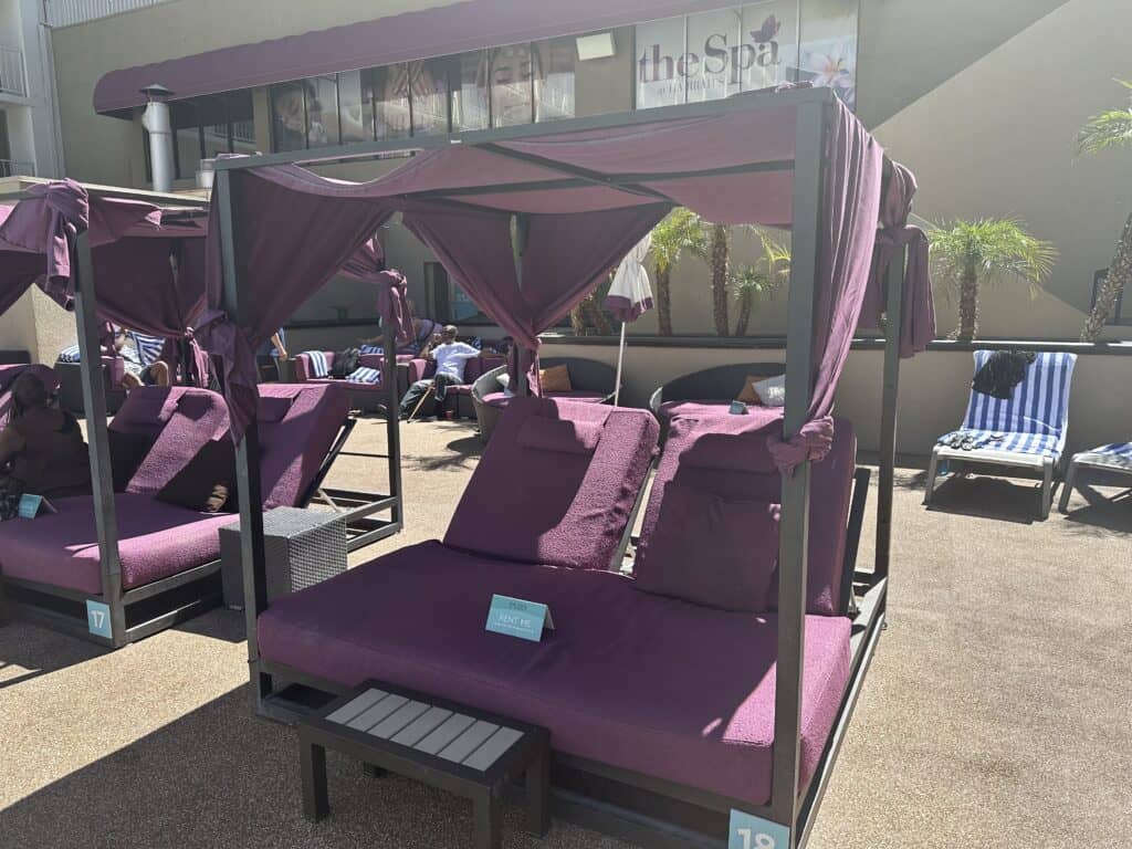 Canopy daybed with purple cushions and awning.