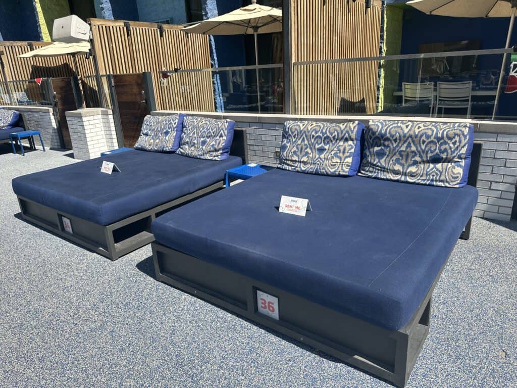 A pair of day beds with rich blue mattress and grey pillows.