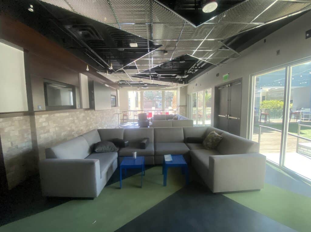 Inside the Req Room showing to large sectional couches.  Large windows are seen in the background.