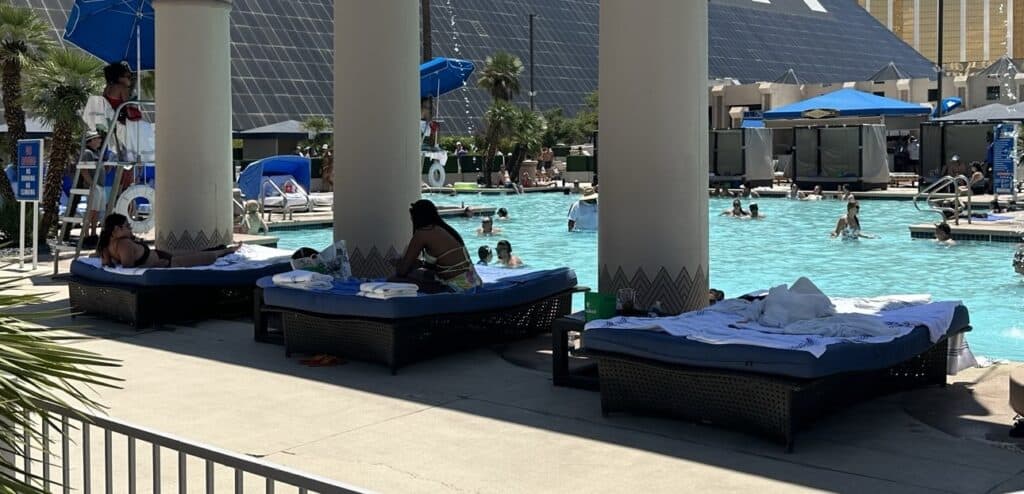 Luxor daybeds  poolside. Guests can seen swimming  in the background