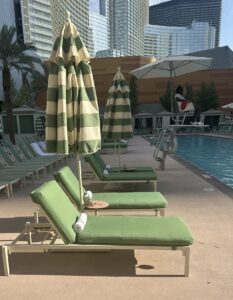 A pair of green cushioned loungers with a sun umbrella.