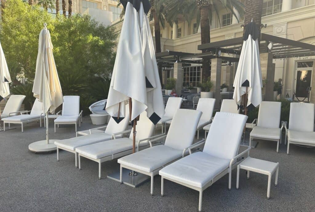 White cushioned loungers with white side tables and white sun umbrellas