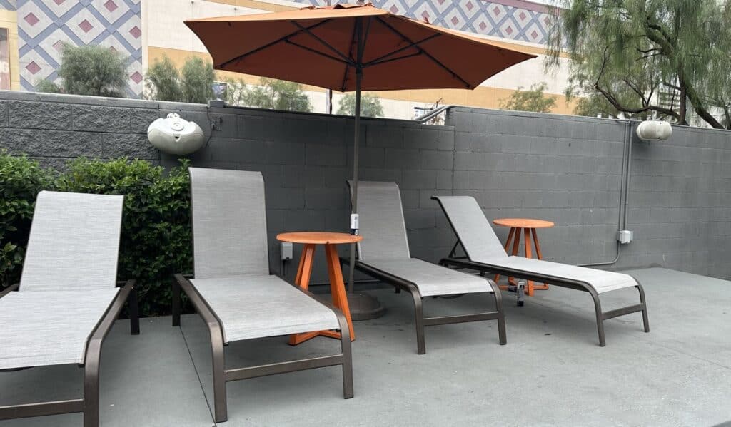 Oasis at Gold Spike loungers with side bles and a large orange sun umbrella overhead.