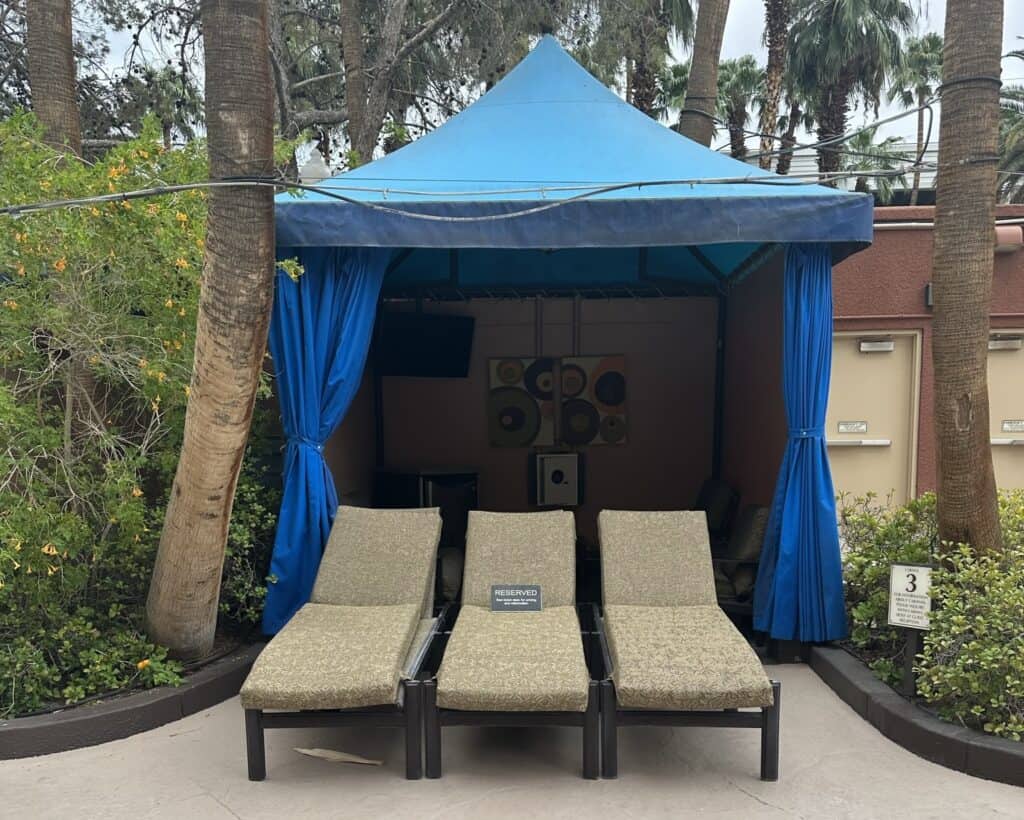 Treasure Island pool cabana with blue roof and sides. 3 luxury loungers are in front.