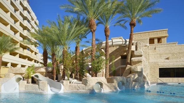 Pool with waterslides. Palm Trees are located just behind the pool.