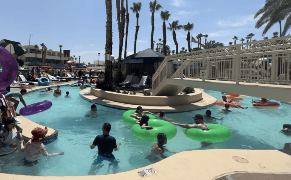 Guests enjoying floating down the Lazy River.  Tall palm trees are in the background.