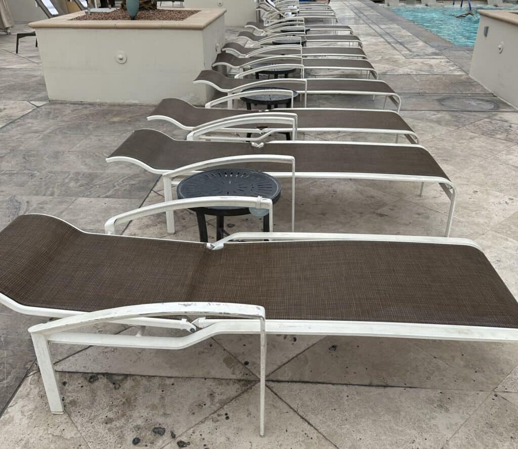 A row of empty loungers line the pool.