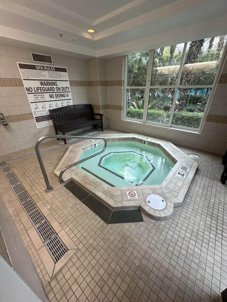 Indoor hot tub with large window looking outside.