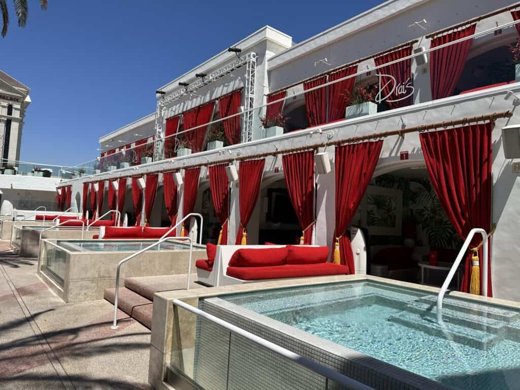 Two levels of red trimmed cabanas in front of a private pool.