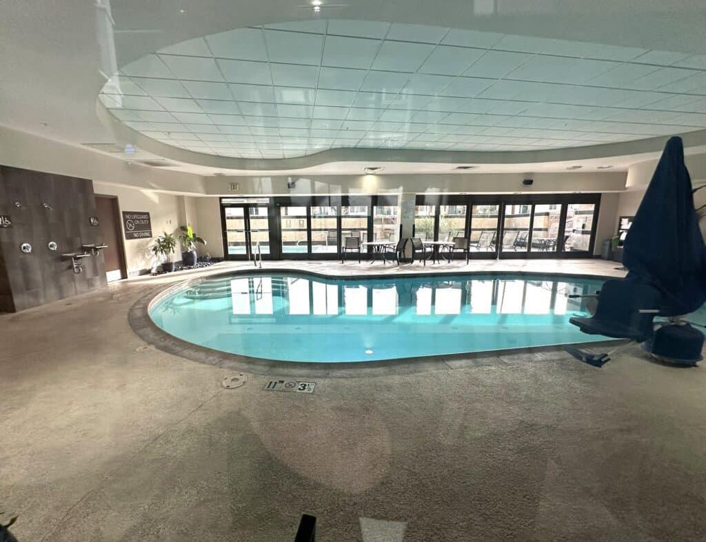 Indoor pool with large folding glass doors leading outside.