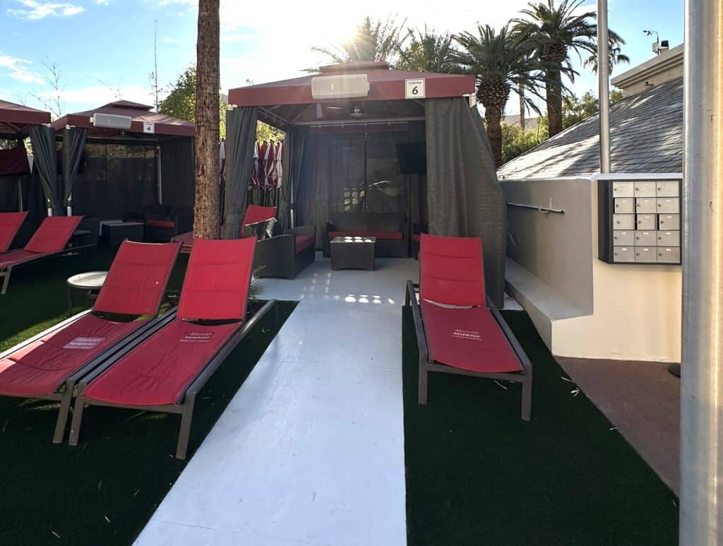 Cabana with 3 red loungers in front.