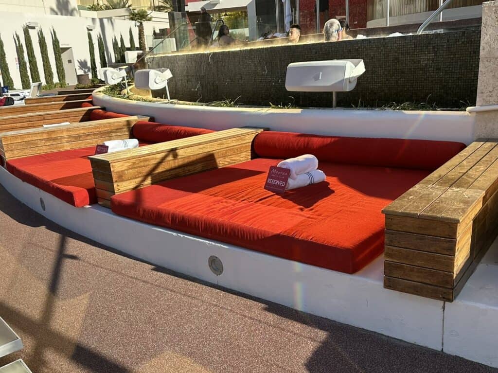Red daybeds with pool towels stacked neatly on them.