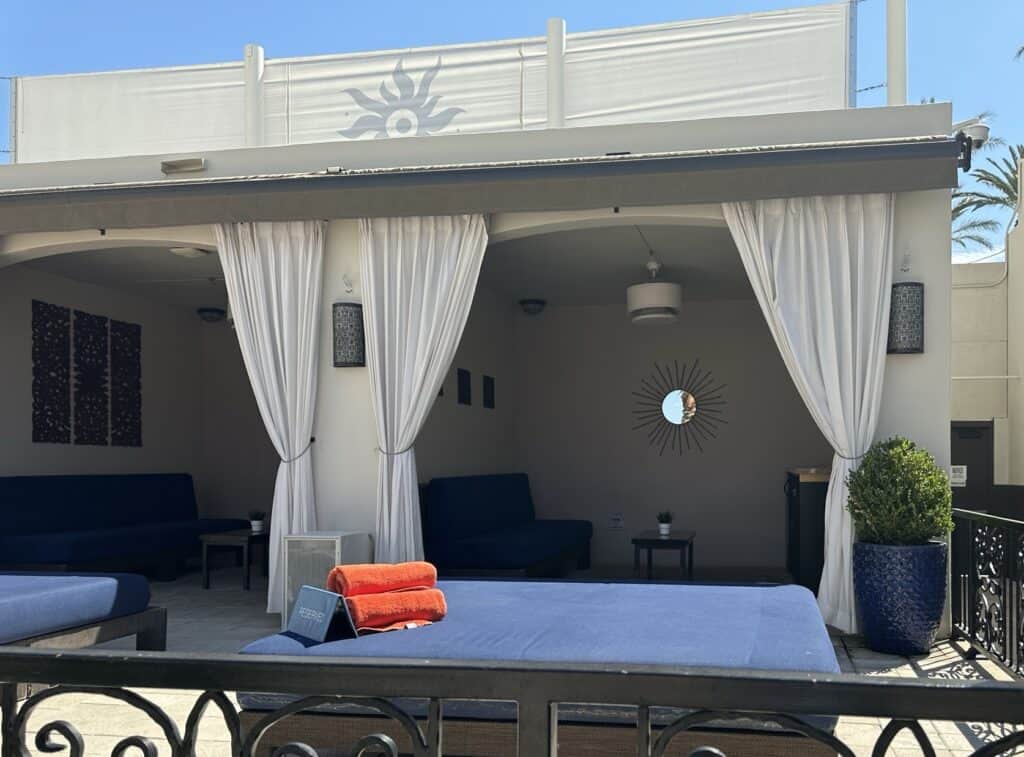 Cabana with a blue daybed with red towels on top.