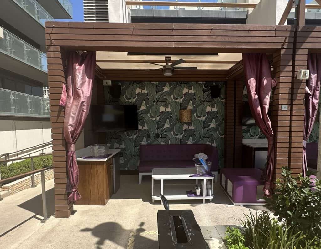 Looking inside a cabana you can see a mounted TV along with seating and storage.