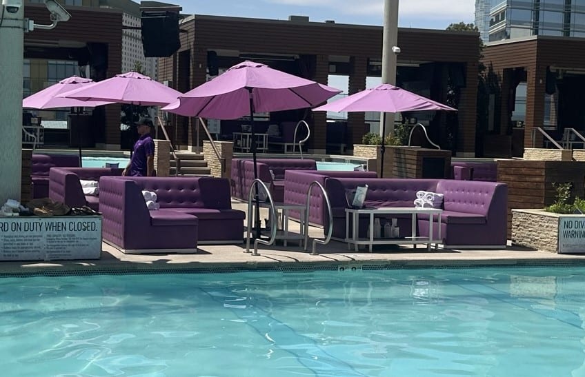 Purple poolside sectional seating with sun umbrellas.