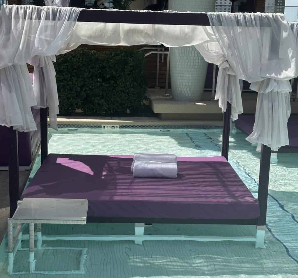 Purple cushioned canopy daybed in shallow water.